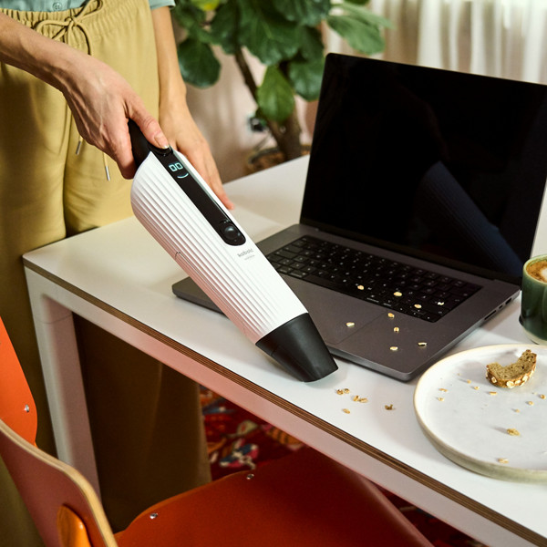 Une femme passe l'aspirateur de table VM7 sur sa table