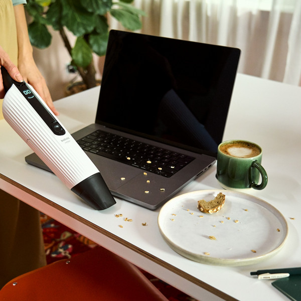 Une femme passe l'aspirateur de table VM7 sur sa table