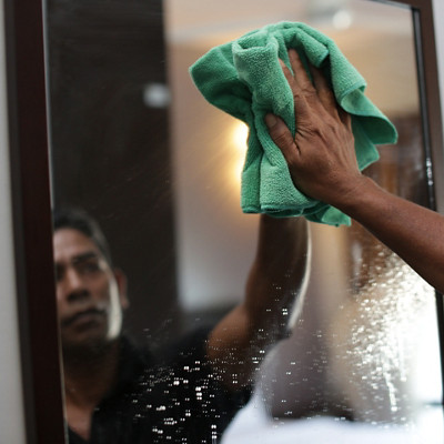 Une femme nettoie son miroir avec une lingette microfibre