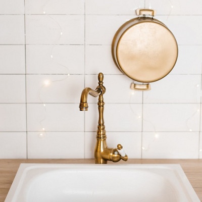 Evier blanc avec un robinet couleur or et du carrelage blanc au mur