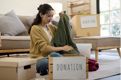 Femme qui trie ses vêtements et des cartons de donations
