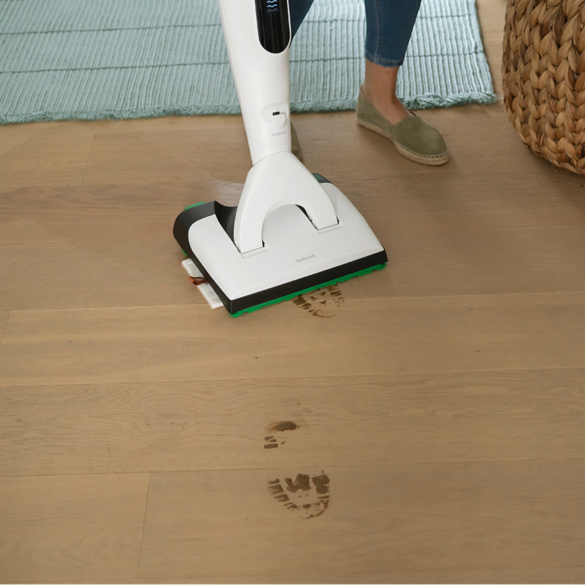 Aspirateur sans fil Kobold VK7 nettoyant des traces boueuses sur un sol en bois.