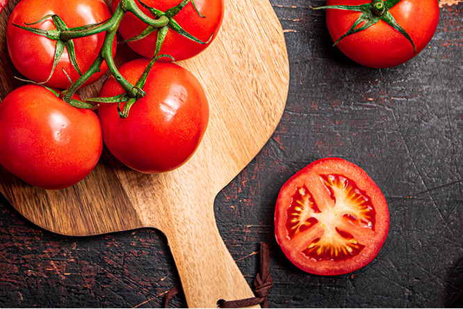 Fresh tomatoes on a wooden cutting board. Against a dark background. High quality photo