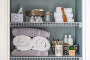 Neatly organized bathroom linen closet with bamboo toothbrushes and white towels