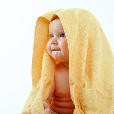 Adorable happy baby in yellow towel on white background