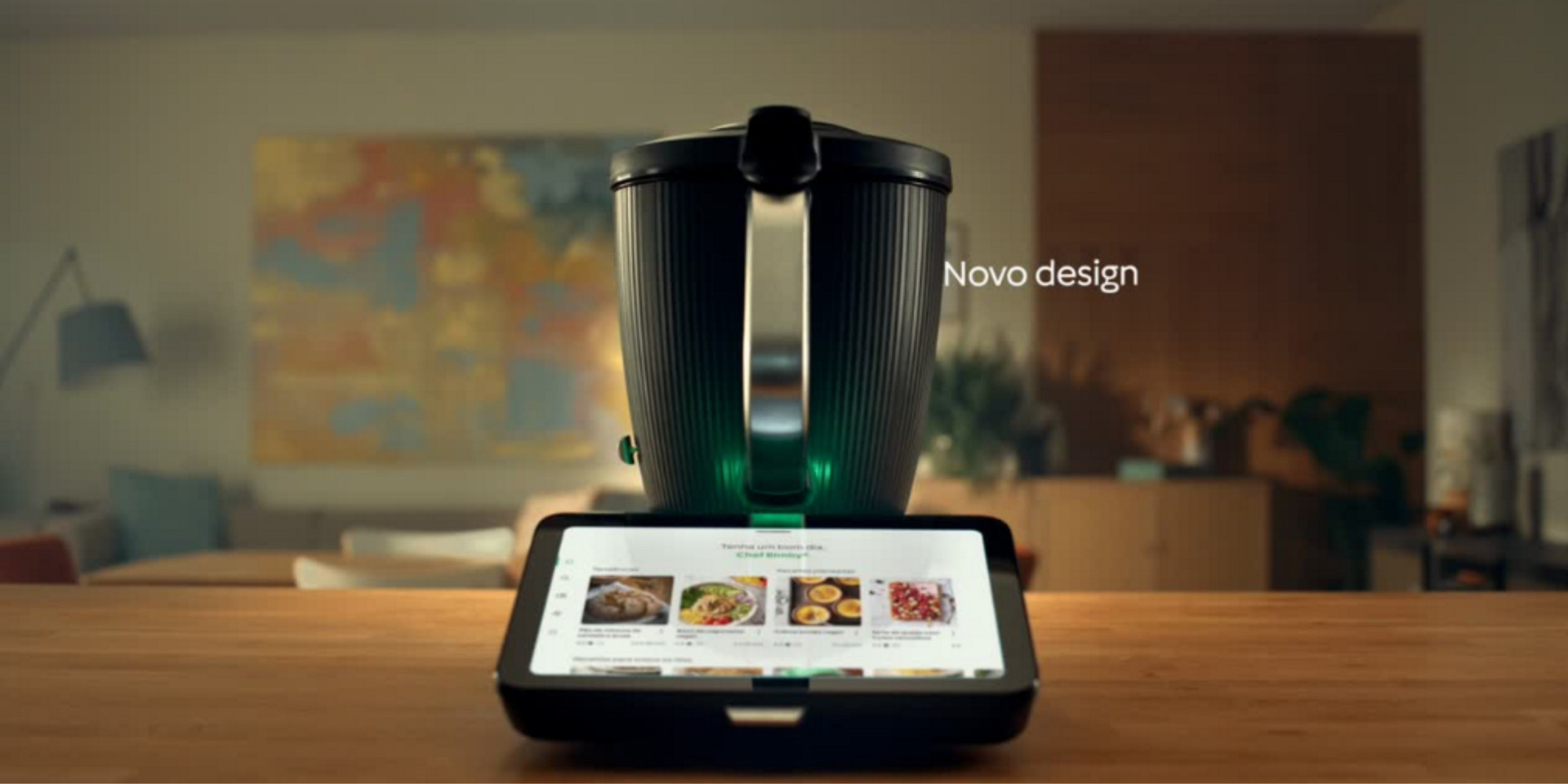 Bimby® TM7 sobre bancada de cozinha com visor de receitas, fundo desfocado, texto “Novo design”.