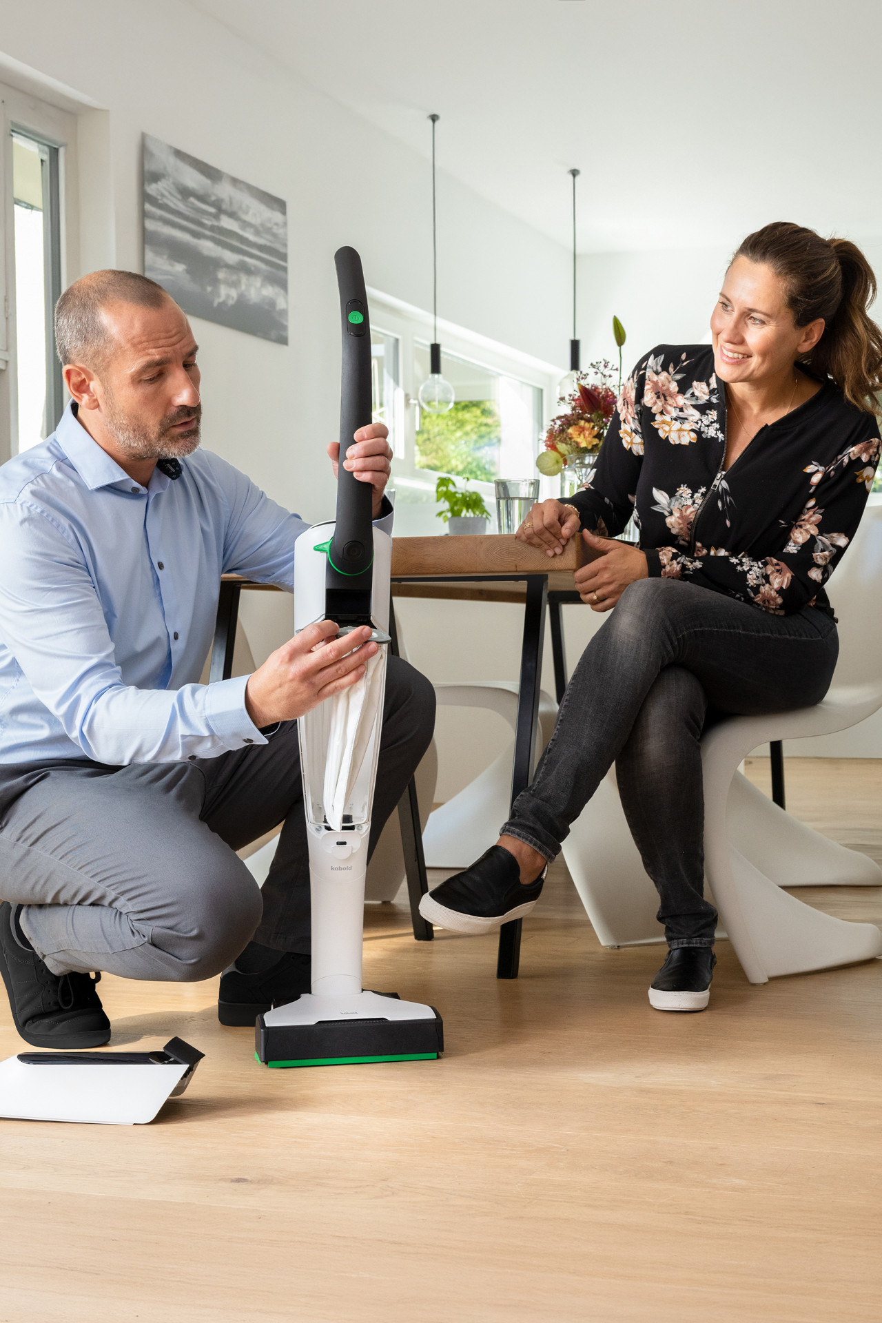 Ein Mann erklärt einem Paar Teile eines Kobold Staubsaugers