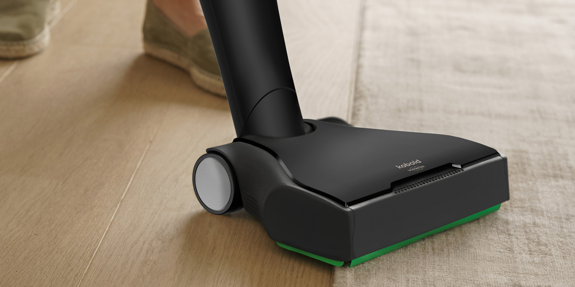 Akku-Staubsauger in Schwarz saugt auf Teppich und Laminat