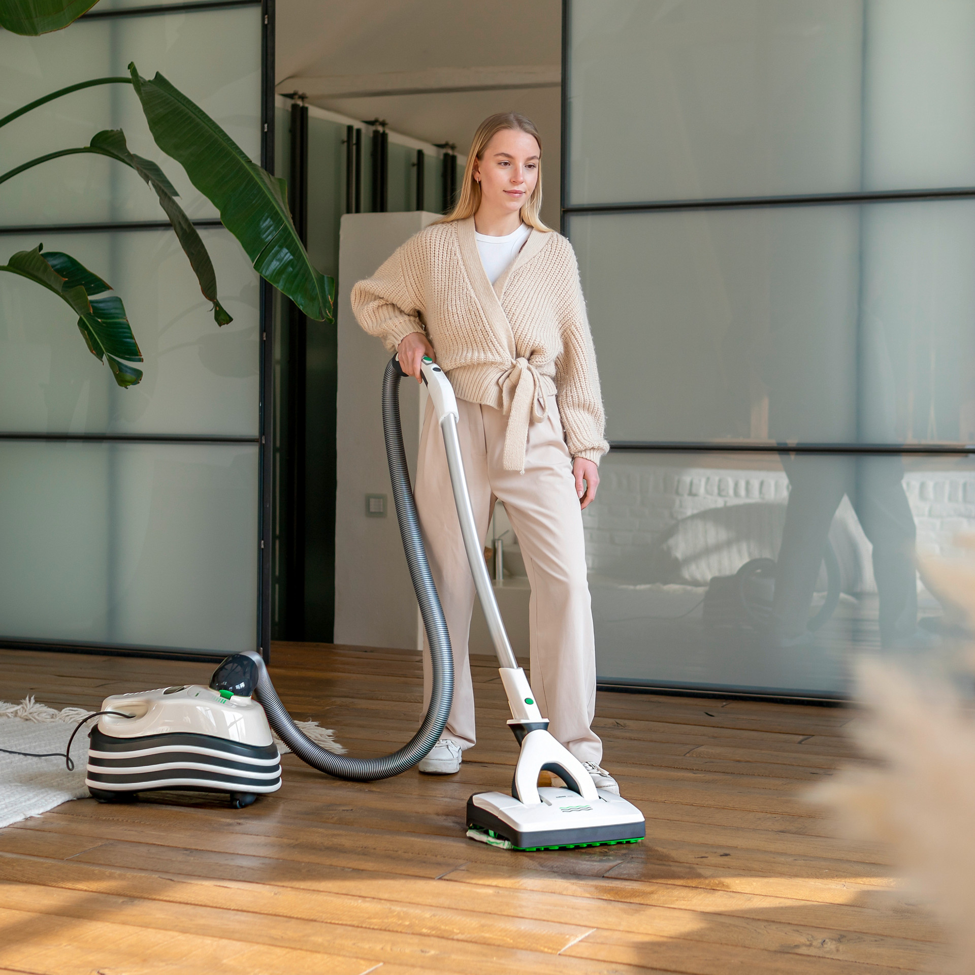 Person reinigt Holzfußboden mit Kobold VT300 in modernem Wohnzimmer.