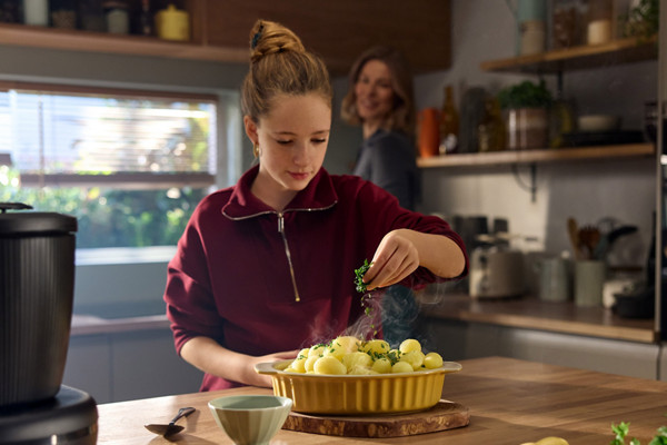 Kind würzt Kartoffeln in KÜche mit Thermomix® TM7