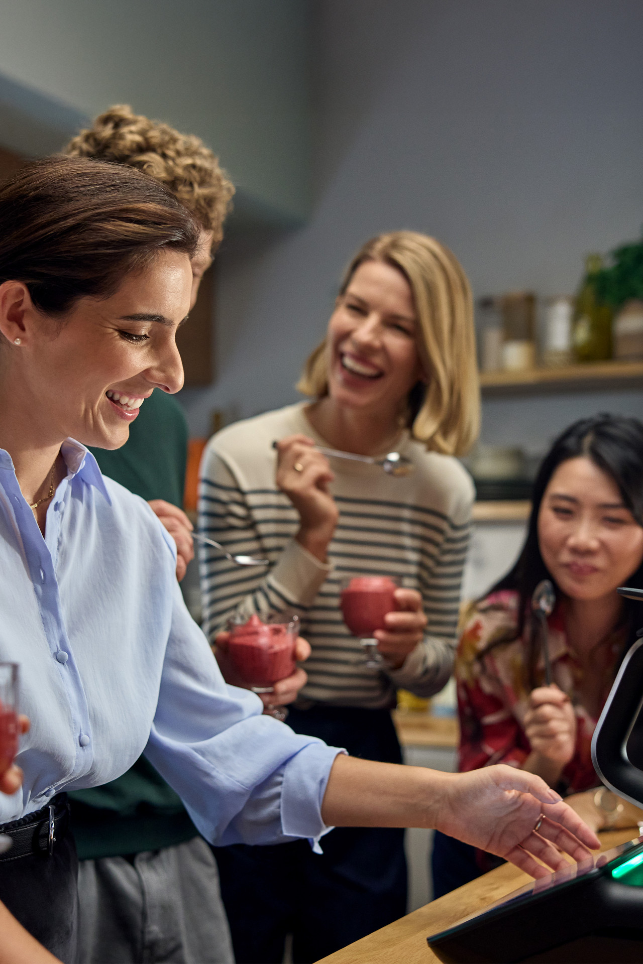 Eine Frau bedient den Thermomix umgeben von lachenden Frauen