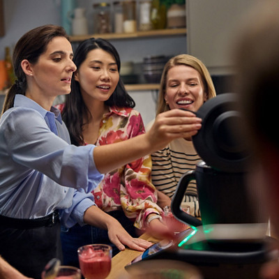 Group of people standing together in kitchen and trying bread