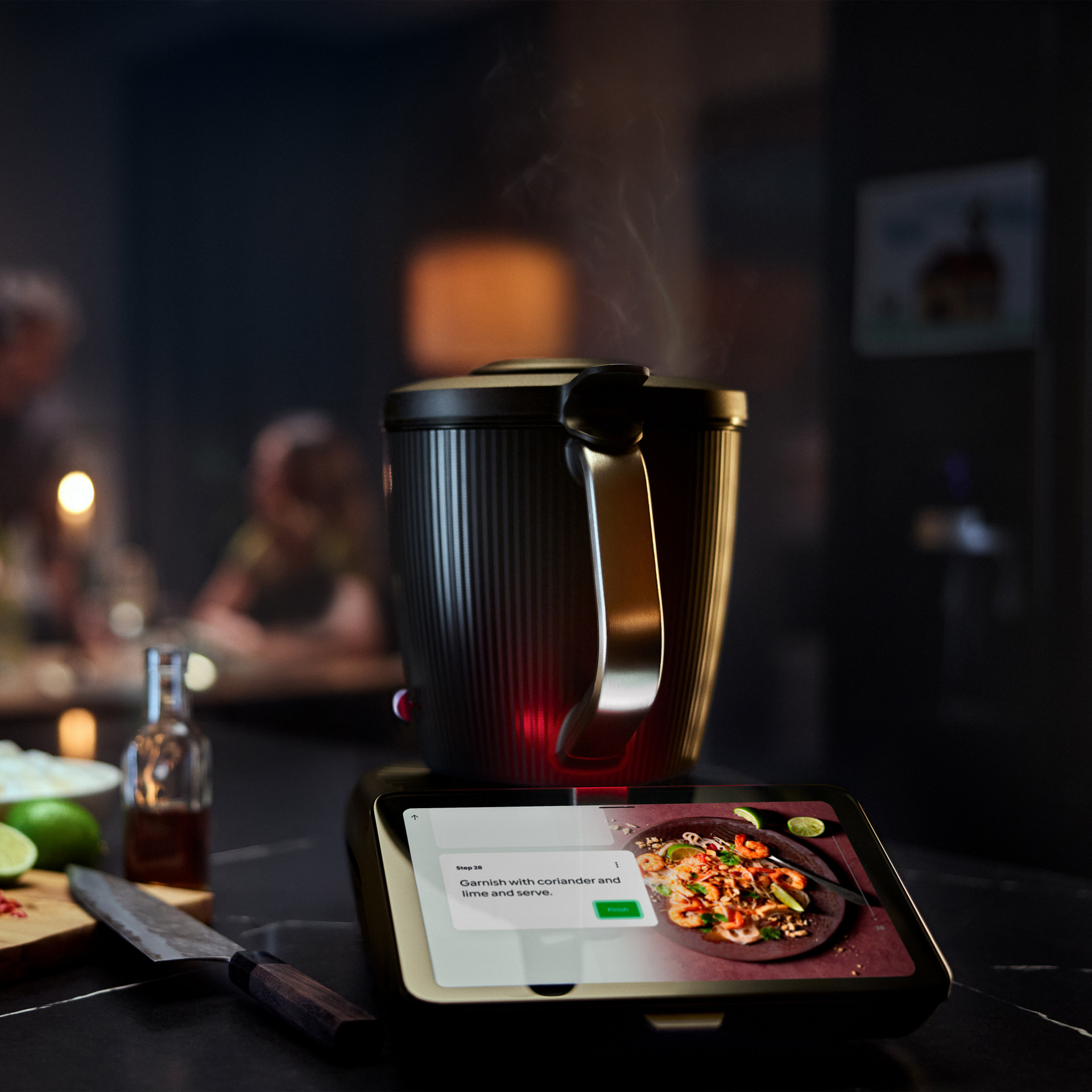 Thermomix® TM7 on a kitchen counter with ingredients and prepared dish visible on its display.