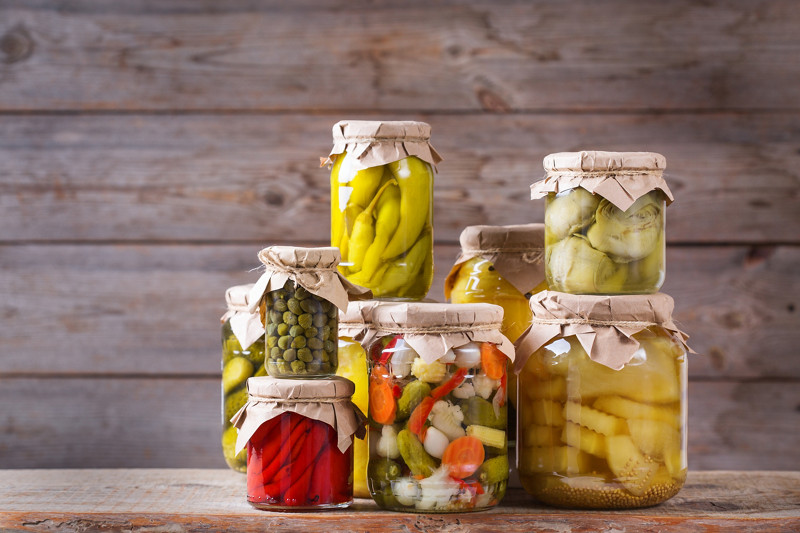 Preserved and fermented food. Assortment of homemade jars with variety of pickled and marinated vegetables on a wooden table. Housekeeping, home economics, harvest preservation  