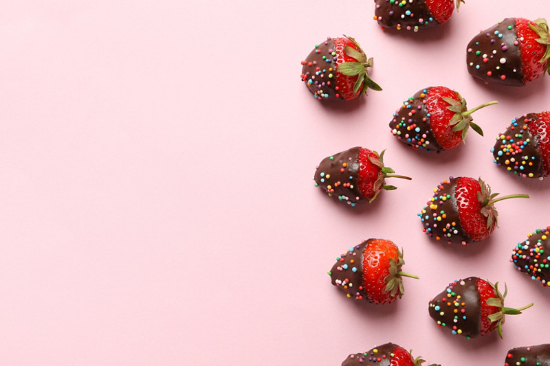 Chocolate fondue. Flat lay with strawberry in chocolate on pink background