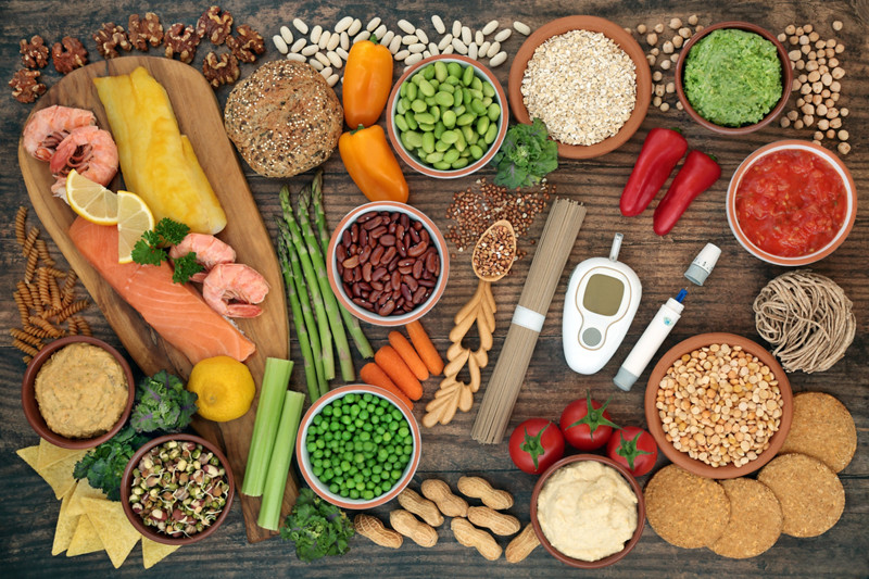 Low glycemic testing & lancing devices with healthy food for diabetics below 55 on the GI index. High in antioxidants, anthocyanins, vitamins, minerals, protein, fibre, omega 3 & smart carbs. Flat lay on wood.