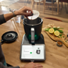 Pessoa insere cobertura de lâmina no Bimby TM7 tablet com instruções ingredientes sobre a mesa