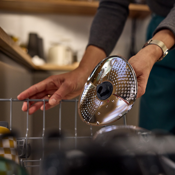 Pessoa coloca um disco Mandolina Bimby em um cesto de máquina de lavar louça na cozinha