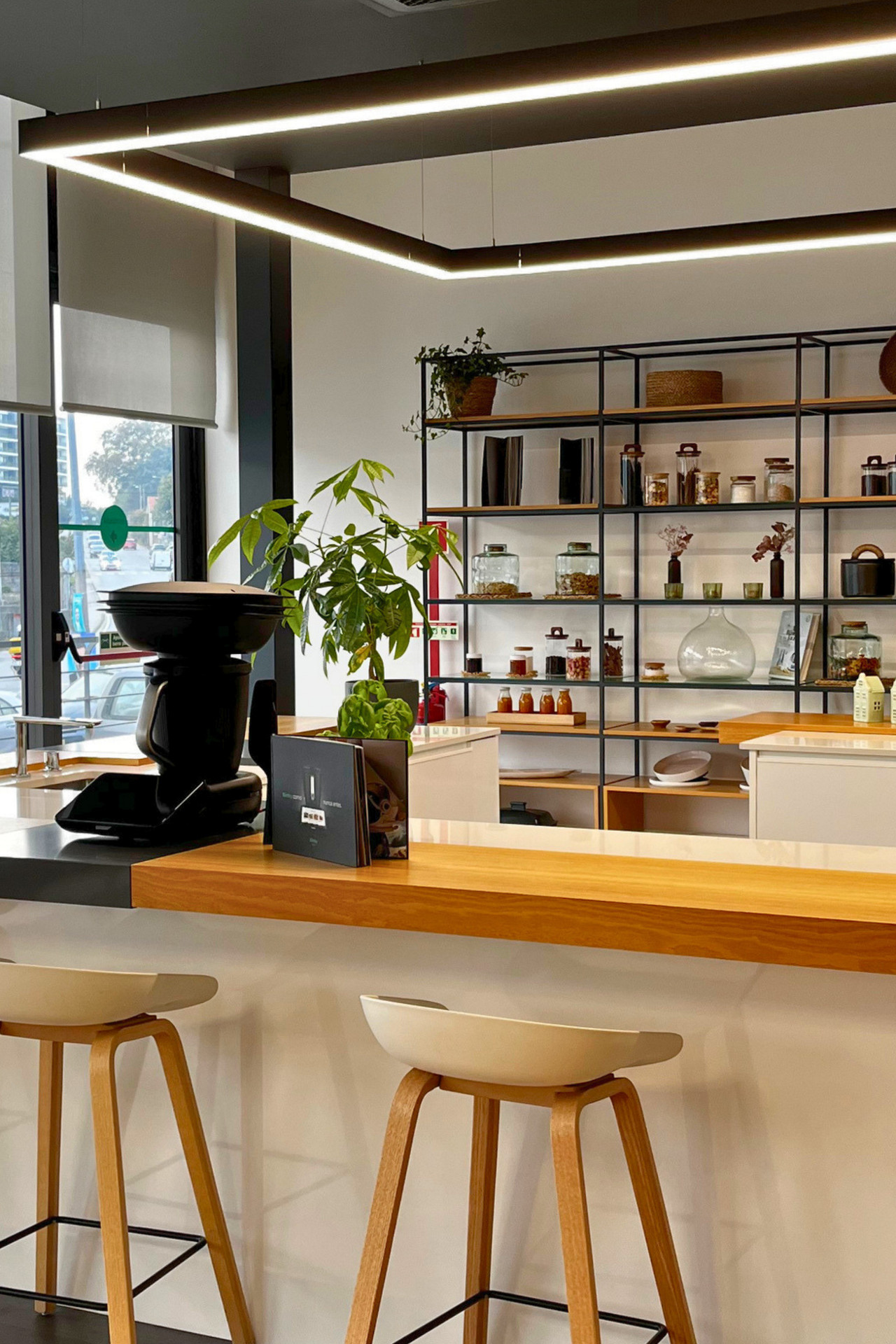 Cozinha moderna com prateleiras, bancos altos, uma planta e Bimby® TM7 no balcão.