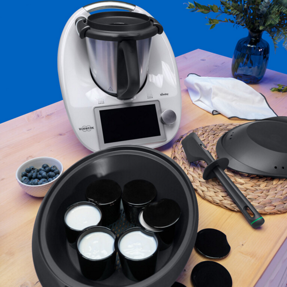 Bimby TM6 com frascos de iogurte Varoma espátula e ingredientes numa mesa de cozinha