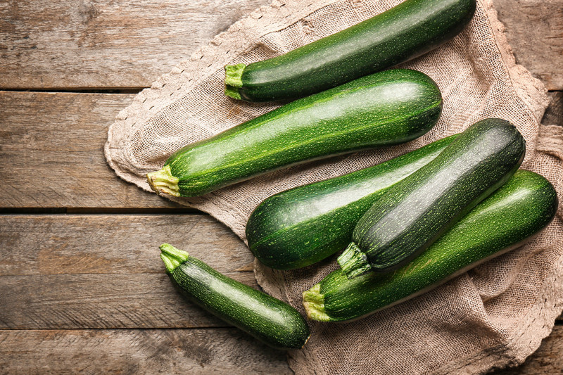 Fresh zucchini squashes on wooden background