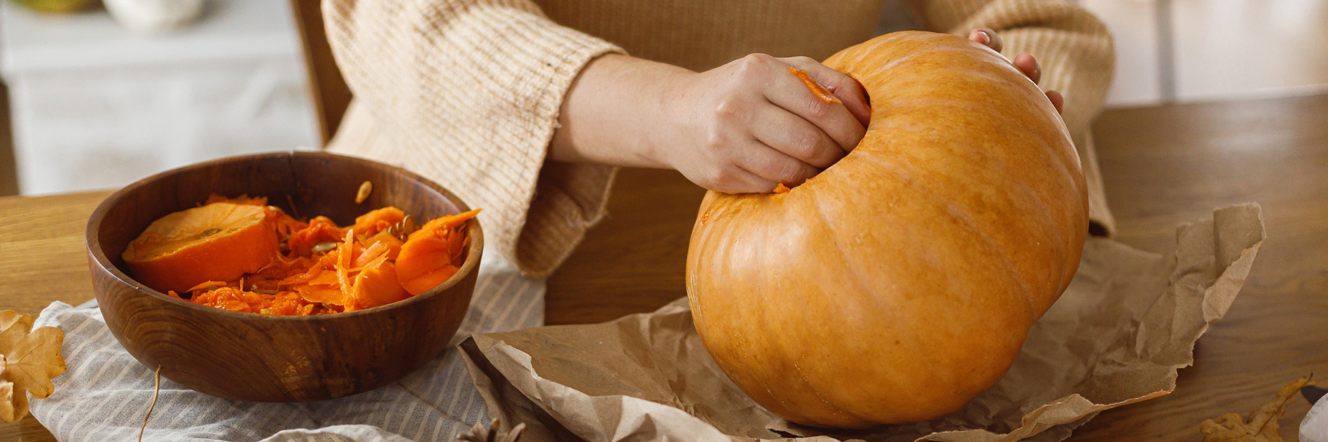 Carving halloween pumpkin. Woman holding pumpkin and gutting on table with ghosts and spiders in living room. Carve a pumpkin, halloween preparation. Making halloween decorations