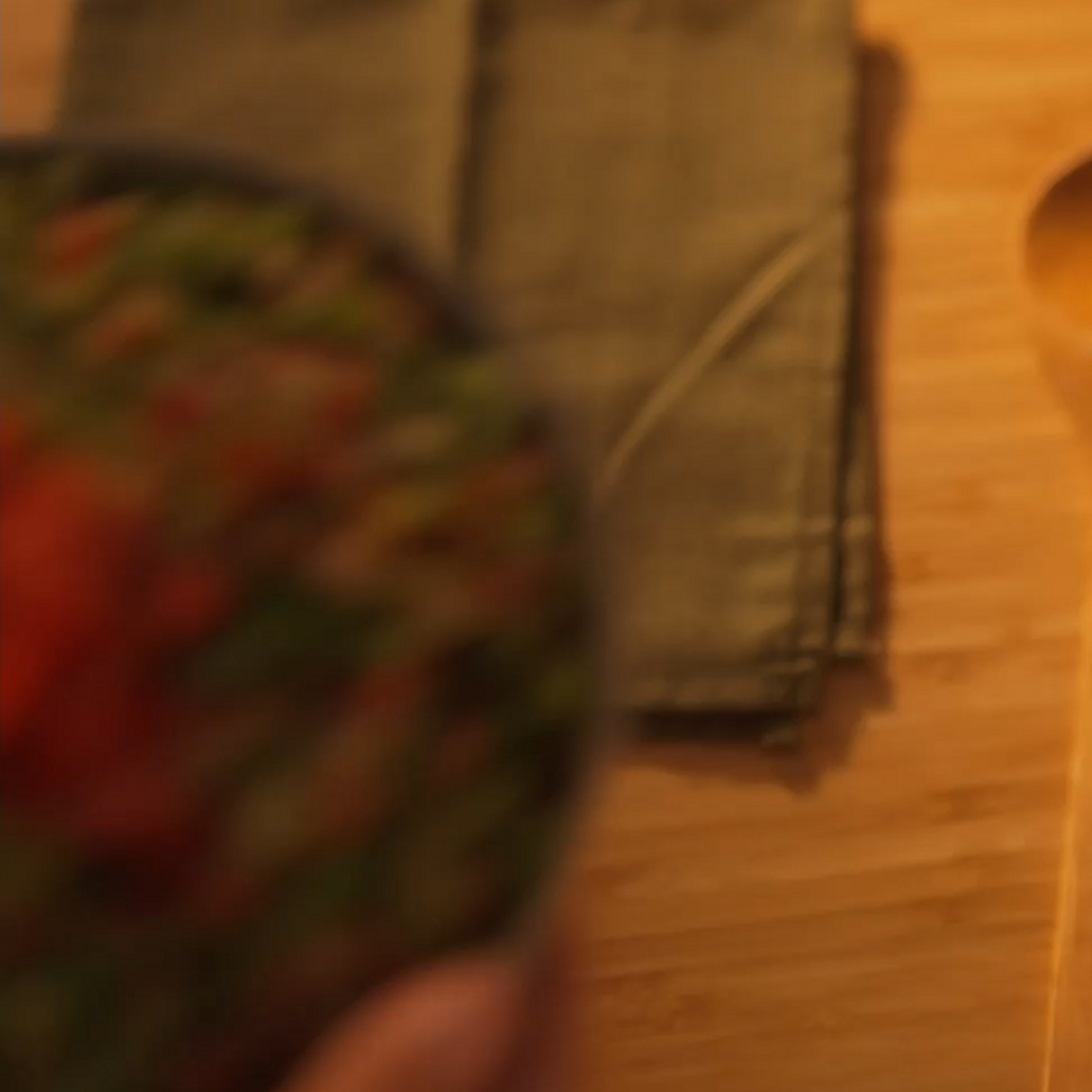 Wooden spoon and cloth napkin on a wooden table, food bowl blurred in foreground.