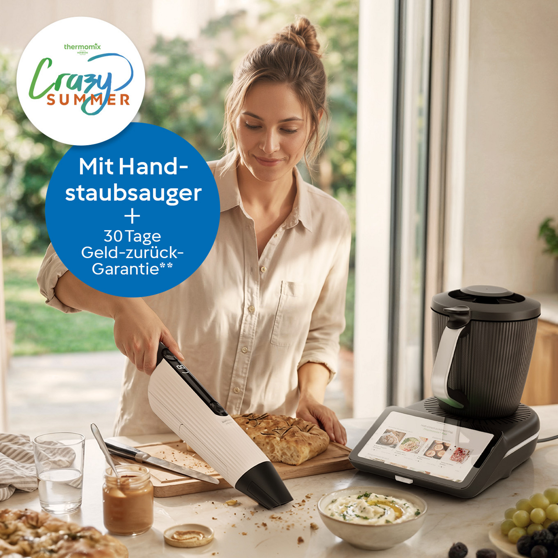 Person nutzt einen Kobold VM7 Akku-Handstaubsauger in einer Küche neben einem Thermomix® TM7, mit „Crazy Summer“-Promotion.