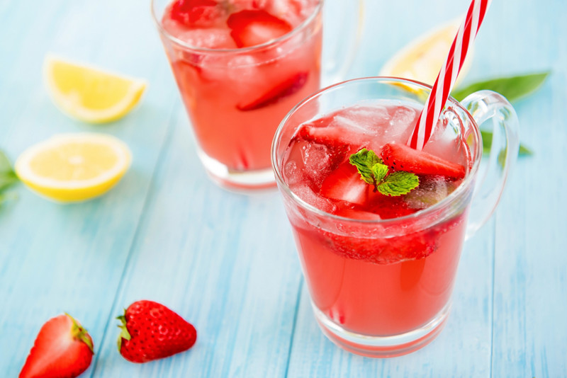 Colorful refreshing drinks for summer, cold sweet and sour strawberry lemonade juice with ice cubes in the glasses