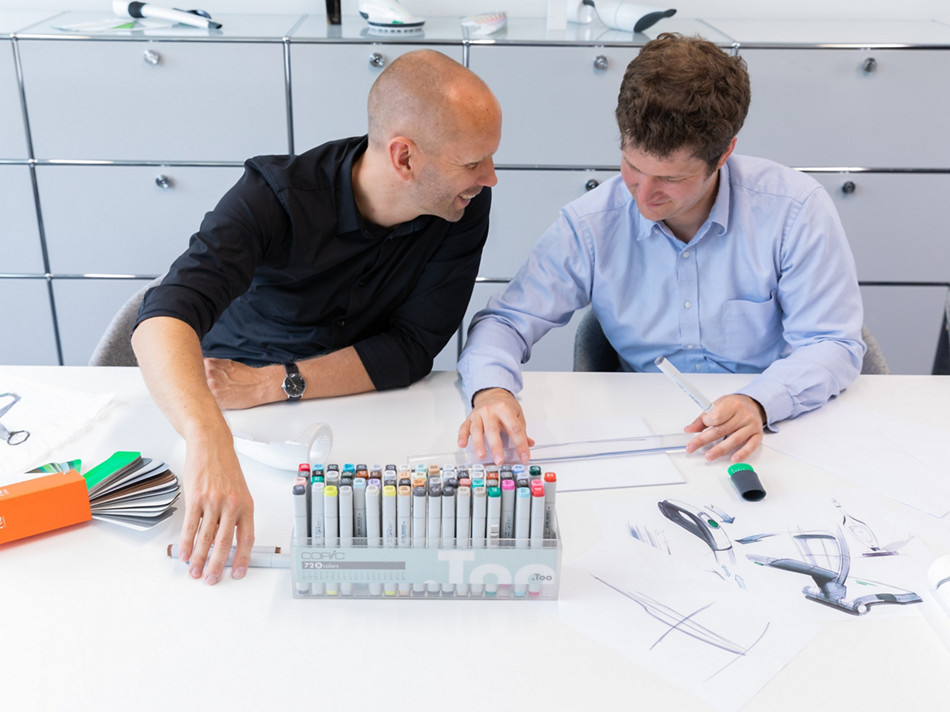 A imagem mostra dois engenheiros discutindo algo um com o outro.